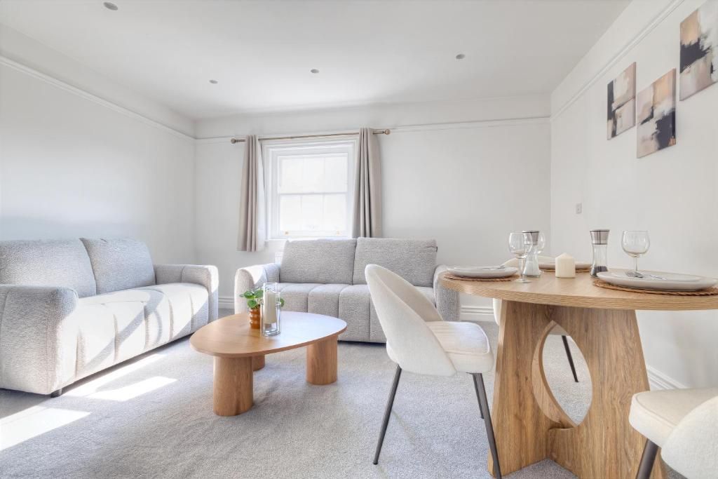 A modern living room with a sofa, a coffee table, and a dining table set for two.