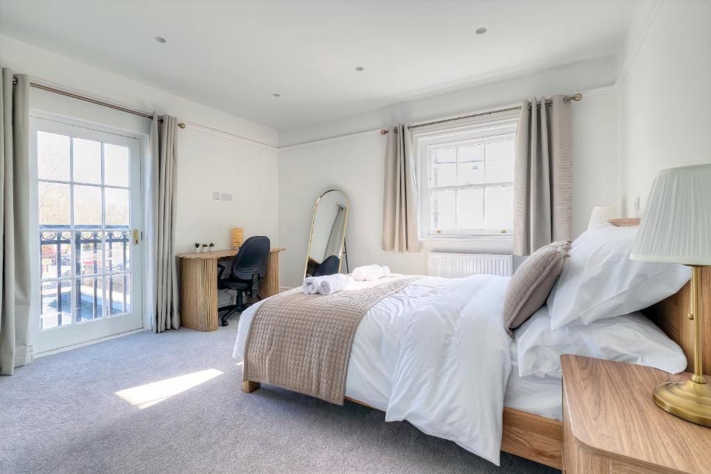 A hotel room with a bed, a desk, a chair, a mirror, and a window.
