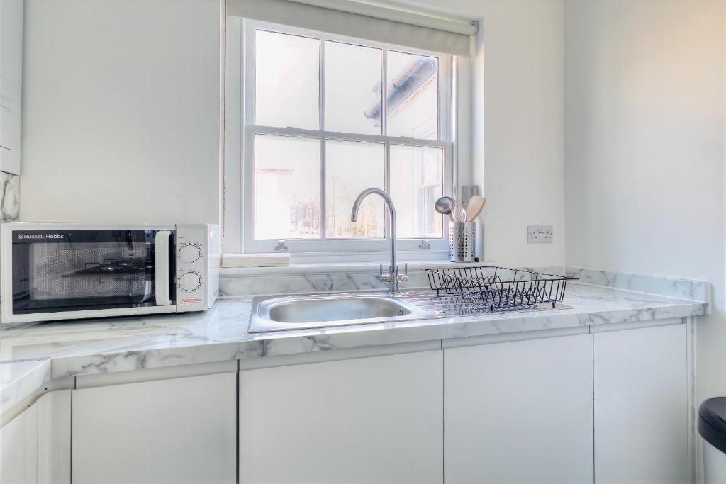 A kitchen with a built-in microwave, a sink with a faucet, and a window above the sink.