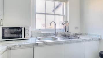 A kitchen with a built-in microwave, a sink with a faucet, and a window above the sink.