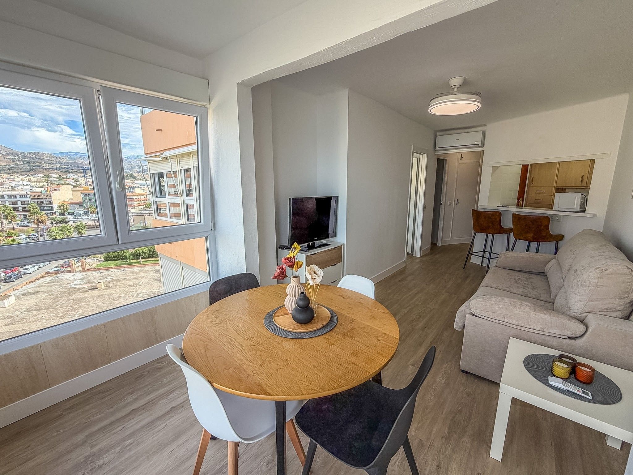 Un salon moderne comprenant un coin repas, un canapé, un téléviseur et une vue sur la ville.