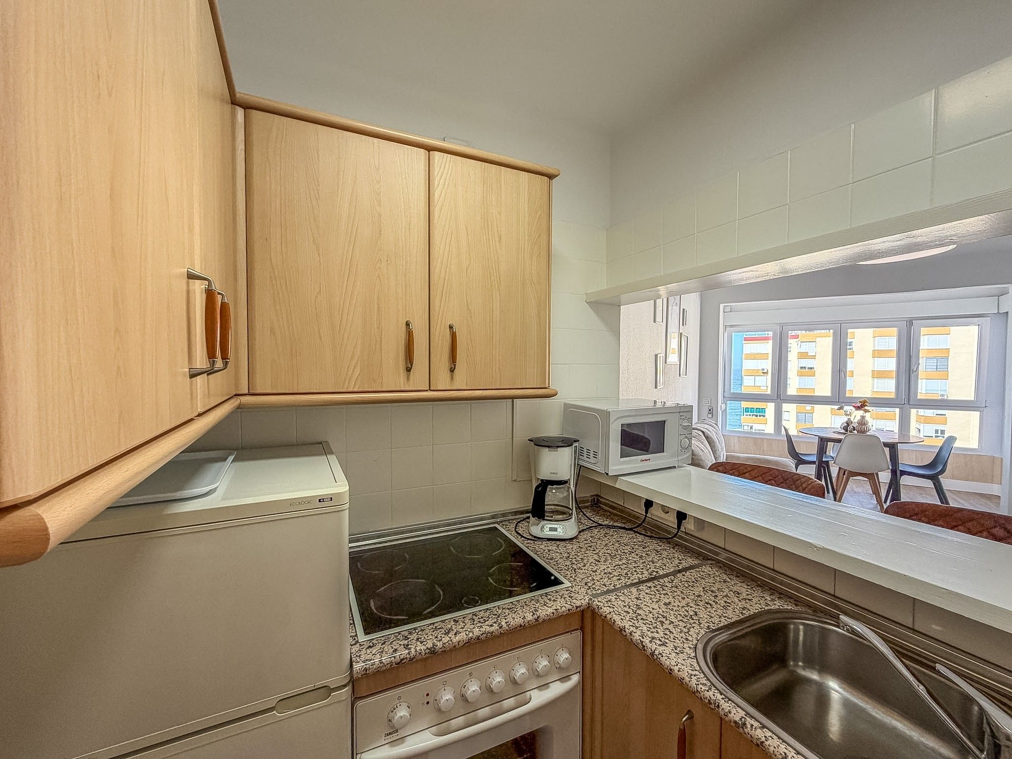 A compact kitchen with wooden cabinets, a built-in stove, a microwave, and a coffee maker.