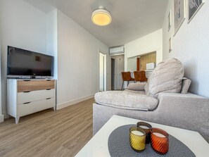 A modern living room with a flat-screen TV, a sofa, a coffee table with candles, and a kitchen area in the background. - Apartment 'Apartamento en primera línea con vistas al mar en Torrox Costa' (Torrox)