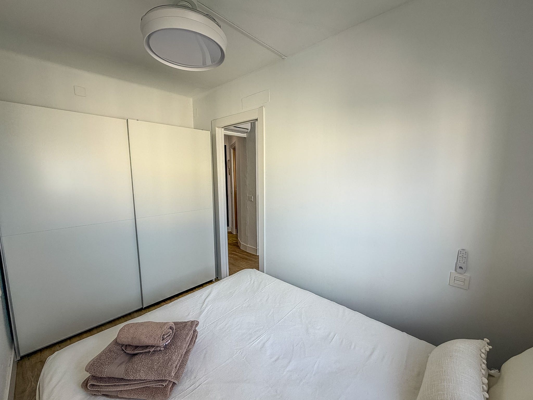 Une chambre à coucher comprenant un lit, une armoire, une porte donnant sur une autre pièce et un luminaire au plafond.