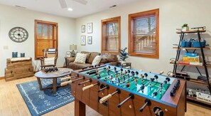 A living room with a foosball table, a sofa, a coffee table, and a bookshelf. - Peek-a-Boo - Eagles Nest, views, foosball, 2 ensuites, log cabin (Banner Elk)