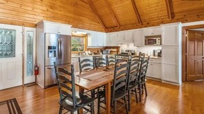 A kitchen with a wooden ceiling, white cabinets, a stainless steel refrigerator, a dining table with chairs, and a microwave. - Peek-a-Boo - Eagles Nest, views, foosball, 2 ensuites, log cabin (Banner Elk)