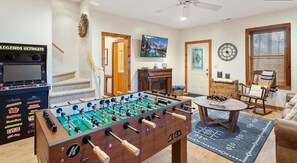 Ein Zimmer mit Tischfußball, Kamin, Fernseher und einer Treppe.