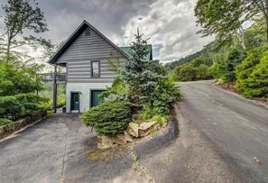 Ein zweistöckiges Haus mit einem Balkon, umgeben von üppiger Vegetation und einer kurvenreichen Straße.