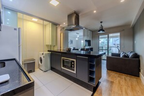 A modern kitchen with a central island, built-in appliances, and a dining area with a sofa. - Matoso by Bhomy (São Paulo)
