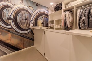Une laverie équipée de plusieurs machines à laver et d’un portant à vêtements.