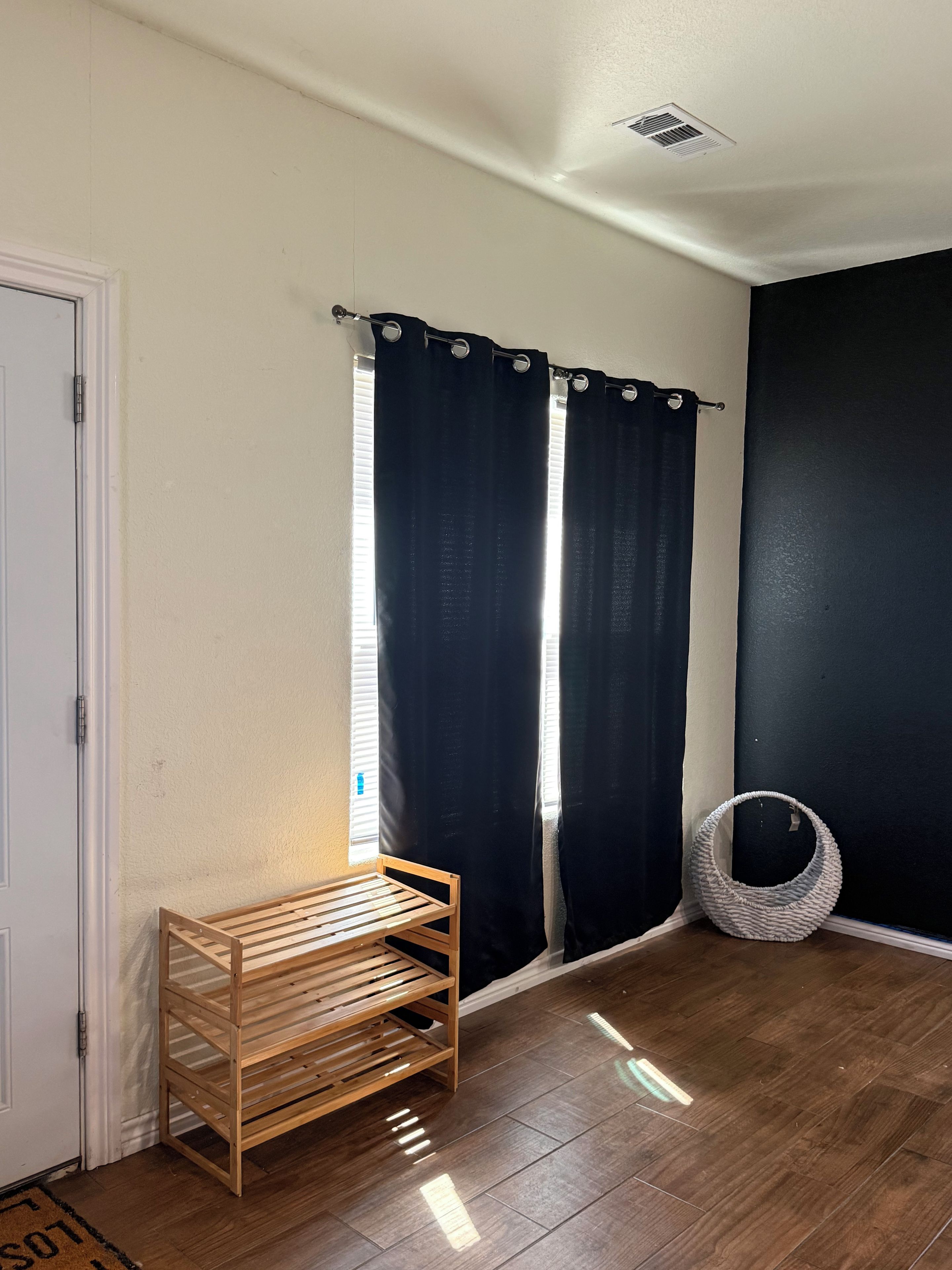 A room with a wooden bench, a woven basket, and a door with a doormat.
