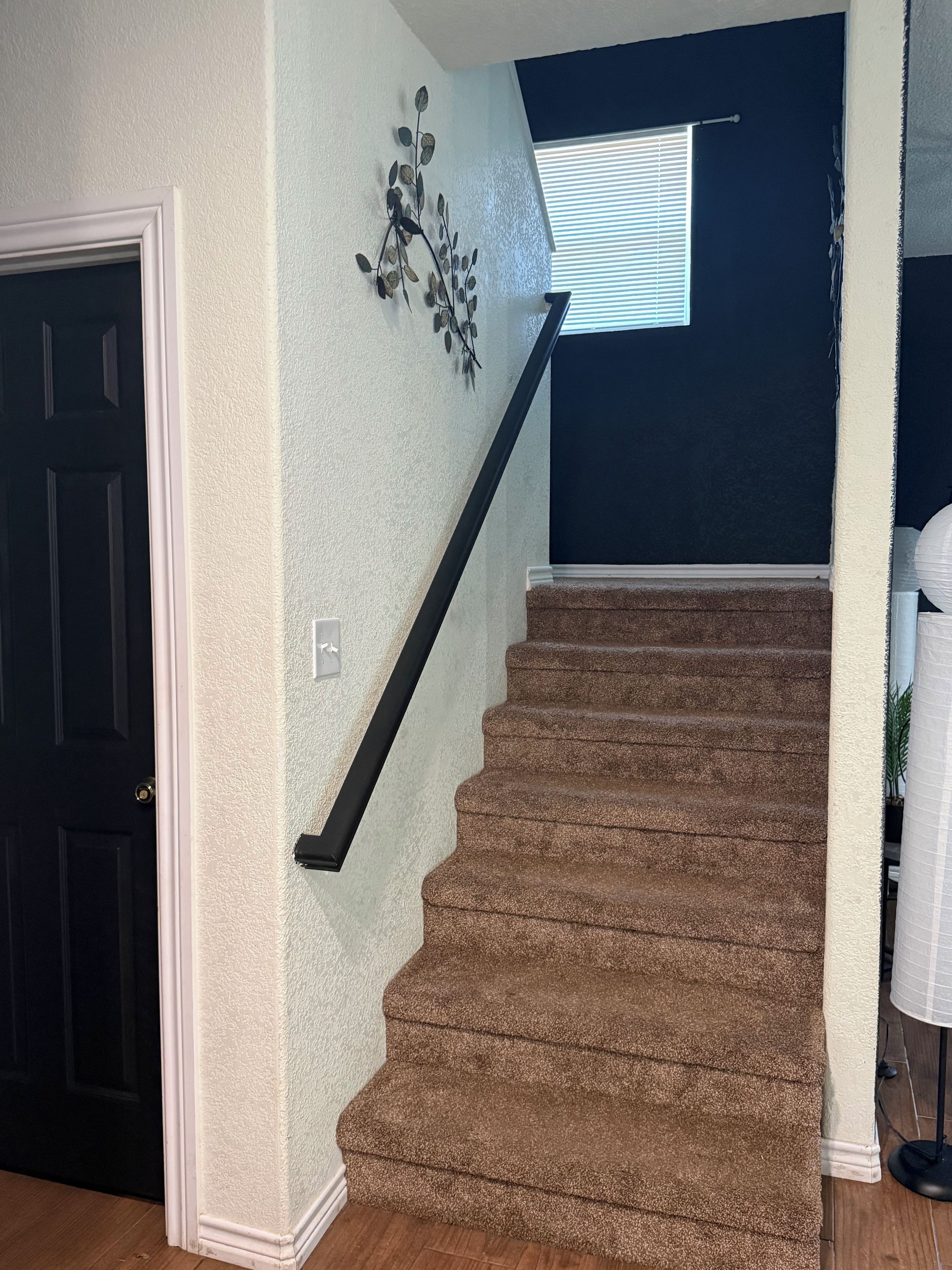 A staircase with a textured wall and a decorative wall art piece.