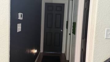 A hallway with a black carpet leading to a door with a white frame.