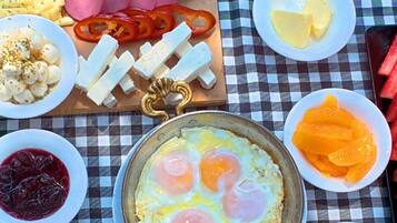 Una mesa con diversos platos, incluyendo huevos, queso y frutas, sobre un mantel a cuadros.