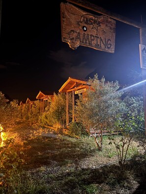 A wooden sign with 'CAMPING' written on it, surrounded by a rustic outdoor setting with wooden structures and vegetation. - Alpstar Camping & Restaurant (Geyikbayiri)
