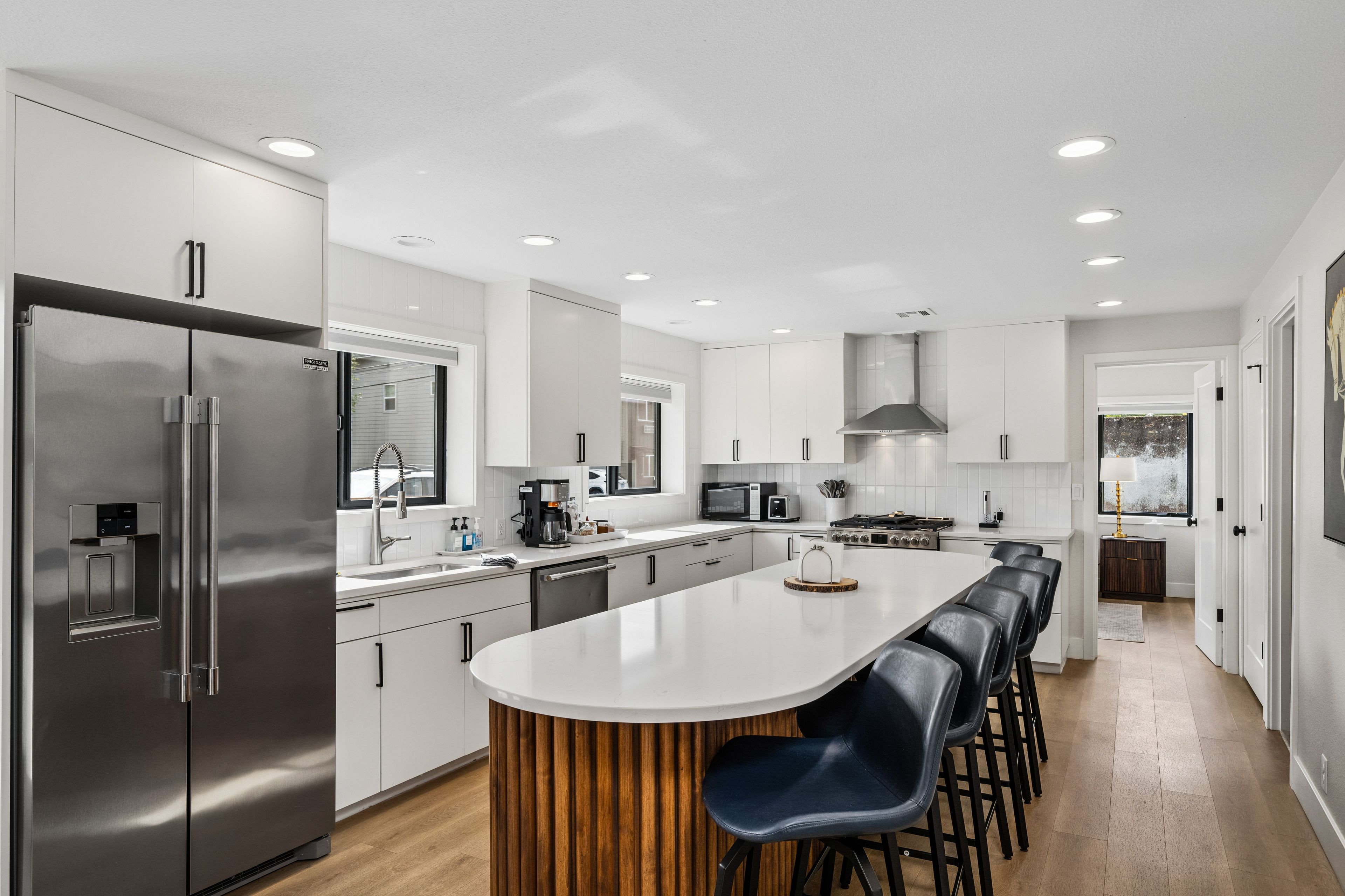 Una cocina moderna con una isla central, electrodomésticos de acero inoxidable y una pared de acento de madera.