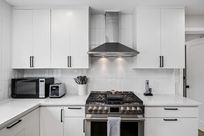 A modern kitchen with white cabinets, a stainless steel range, a microwave, and a toaster. - South Campus Modern - Upscale & Walkable To Uo, Park & Shops 3 Bedroom Home (Eugene)