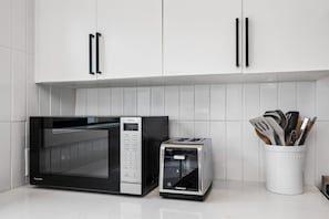 A kitchen with a microwave, toaster, and utensil holder. - South Campus Modern - Upscale & Walkable To Uo, Park & Shops 3 Bedroom Home (Eugene)