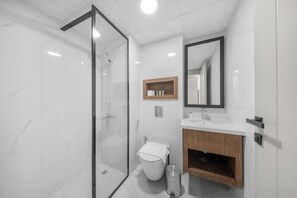 Ein modernes Badezimmer mit einer gläsernen Duschkabine, einer Toilette, einem Waschbecken und einem hölzernen Waschtisch.