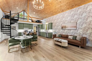 Amplio espacio tipo loft con techo de madera, una escalera de caracol, un comedor, un sofá y una cocina al fondo.
