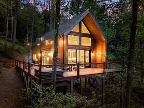 A wooden cabin with a deck, large windows, and a staircase.