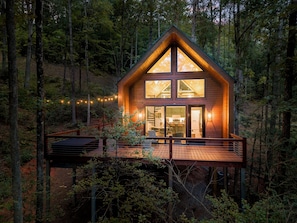 A wooden cabin with a deck, large windows, and a staircase leading to the entrance. - This resort is a 9 bedroom(s), 5 bathrooms, located in Cleveland, GA. (Cleveland)