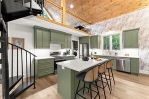 A modern kitchen with green cabinets, a central island, and a black staircase. - This resort is a 9 bedroom(s), 5 bathrooms, located in Cleveland, GA. (Cleveland)