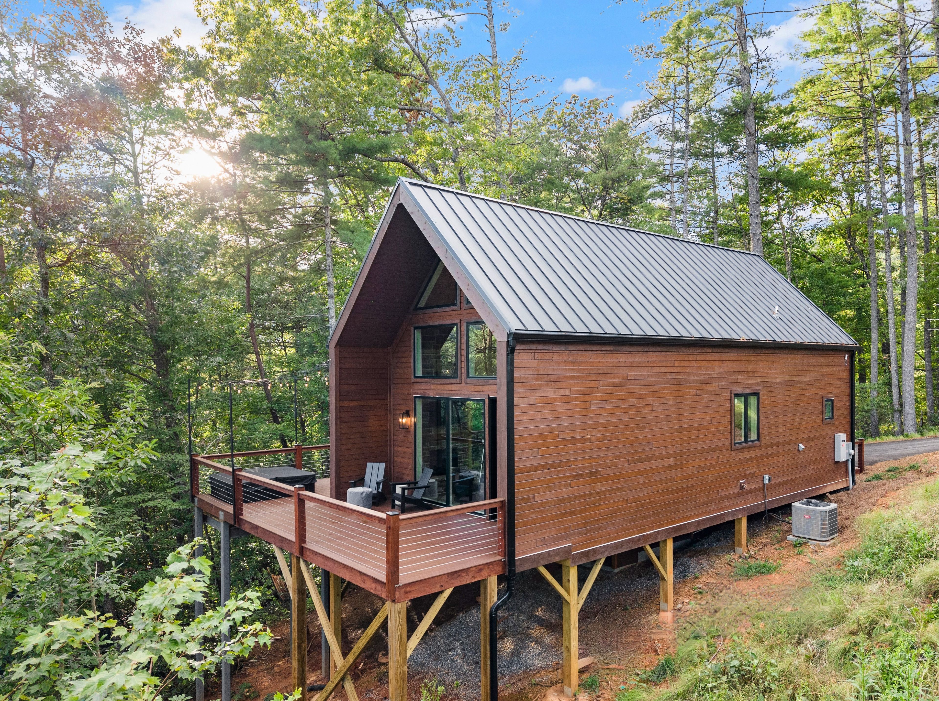 A wooden cabin with a metal roof, a deck, and a glass door.