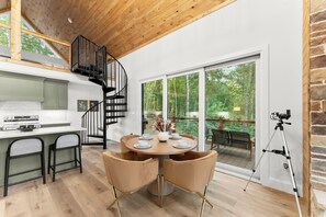 Una cocina moderna con comedor, una escalera en espiral y un amplio ventanal corredera que da a una terraza exterior.