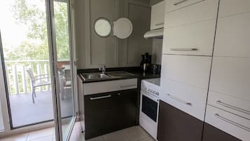 Eine moderne Küche mit Einbauofen, Kaffeemaschine und einer Glastür zum Balkon.