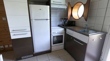 A compact kitchen with a refrigerator, stove, oven, and sink.