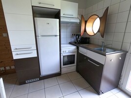 Eine kleine Küche mit Kühlschrank, Herd, Backofen und Spüle.
