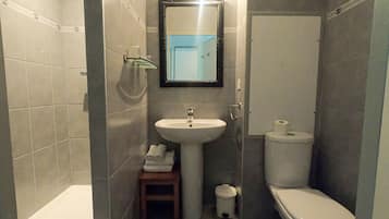 Un bagno compatto con lavabo a piedistallo, un water e un piccolo sgabello con asciugamani.