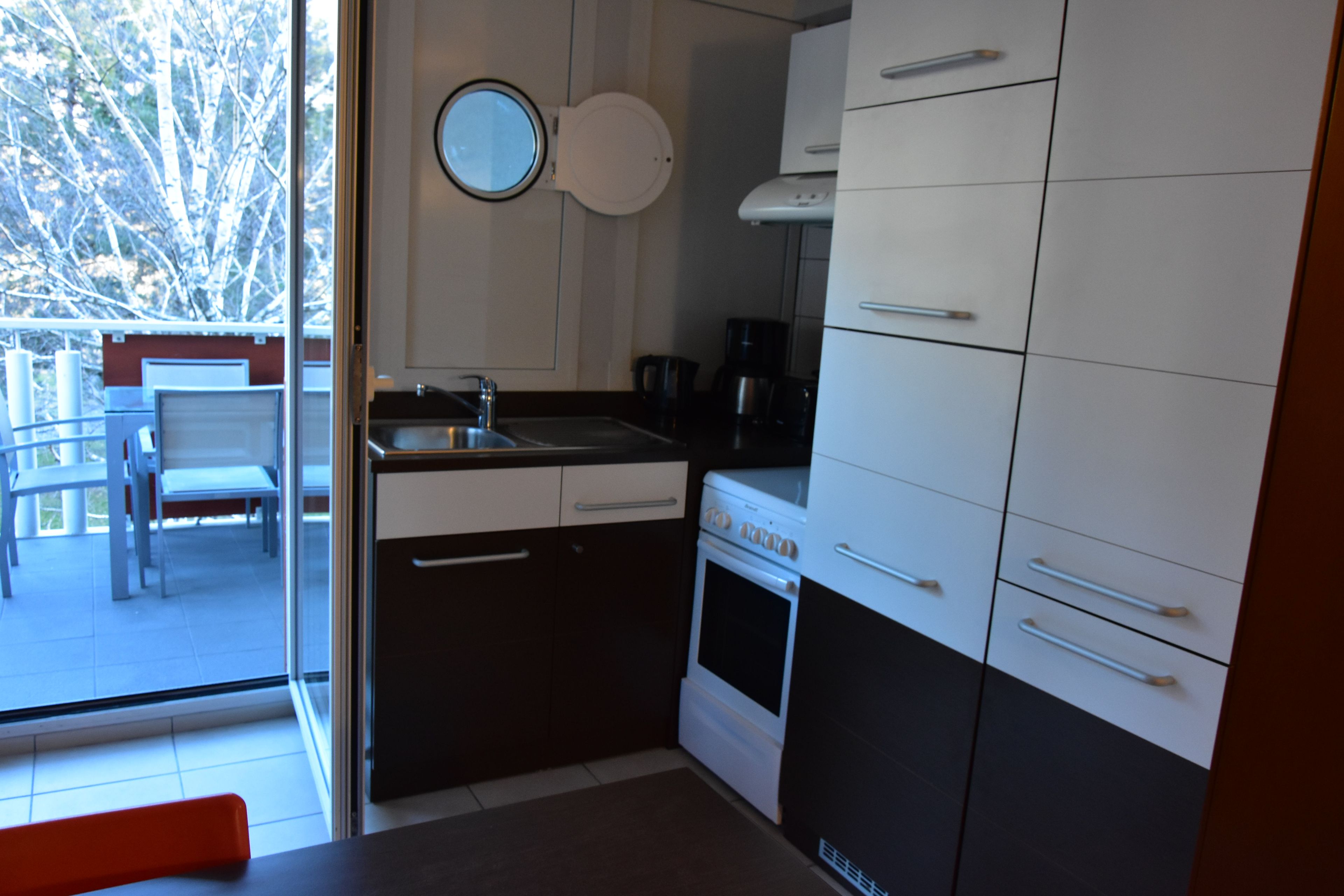 A compact kitchen with a built-in oven, a coffee maker, and a sink.