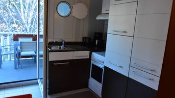 A compact kitchen with a built-in oven, a coffee maker, and a sink.