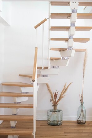 Una escalera con escalones de madera y barandillas blancas, que conduce a un nivel superior.
