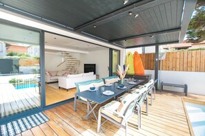 Un área de comedor al aire libre con una mesa lista para cuatro personas, rodeada por una terraza de madera.