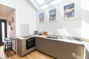 Et moderne køkken med ovenlys, et spiseområde med bord og stole, og tre indrammede kunstværker på væggen.