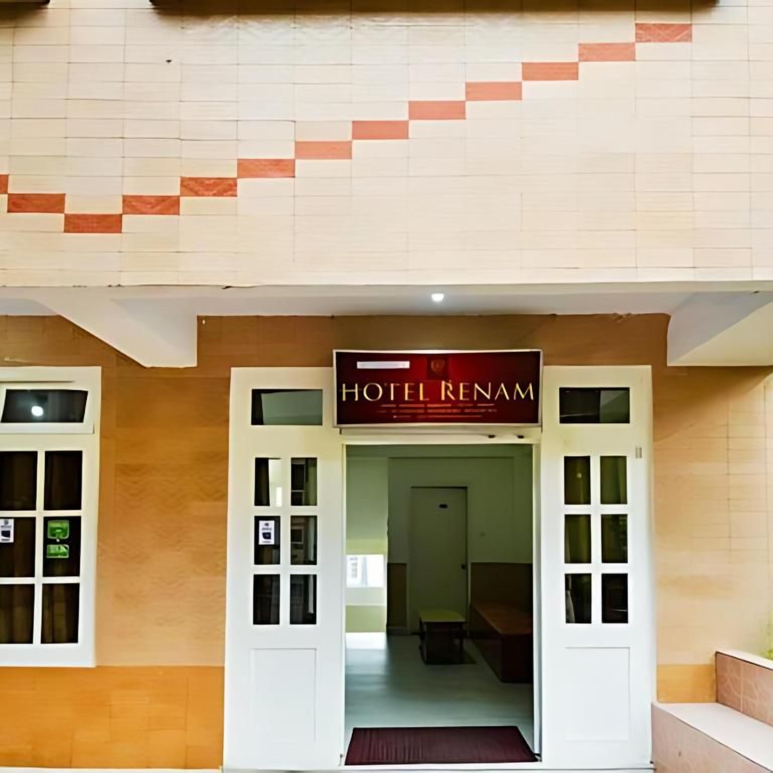 Entrada de un hotel con un letrero que dice 'HOTEL RENAM' y un interior visible, que incluye una recepción y un área de descanso.