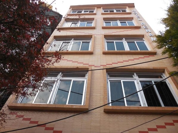 Un edificio de varios pisos con fachada simétrica, ventanas grandes y una placa identificadora visible.