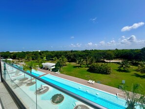 Ein Pool mit freiem Blick auf die umliegende Landschaft, darunter eine Rasenfläche und Bäume.