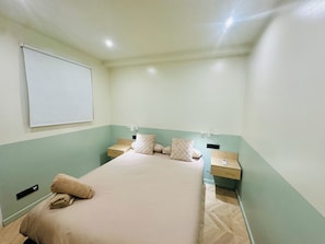A hotel room with a bed, two bedside tables, a wall-mounted TV, and a light switch. - Apartment in Eixample (Barcelona)