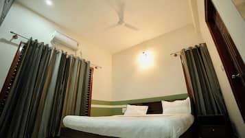 A bedroom with a bed, curtains, an air conditioning unit, a ceiling fan, and a wall-mounted light.