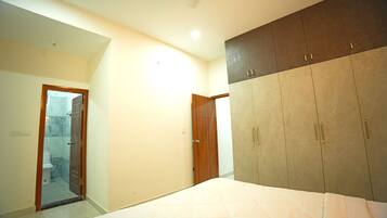A bedroom with a bed, wardrobe, and a bathroom with a shower.