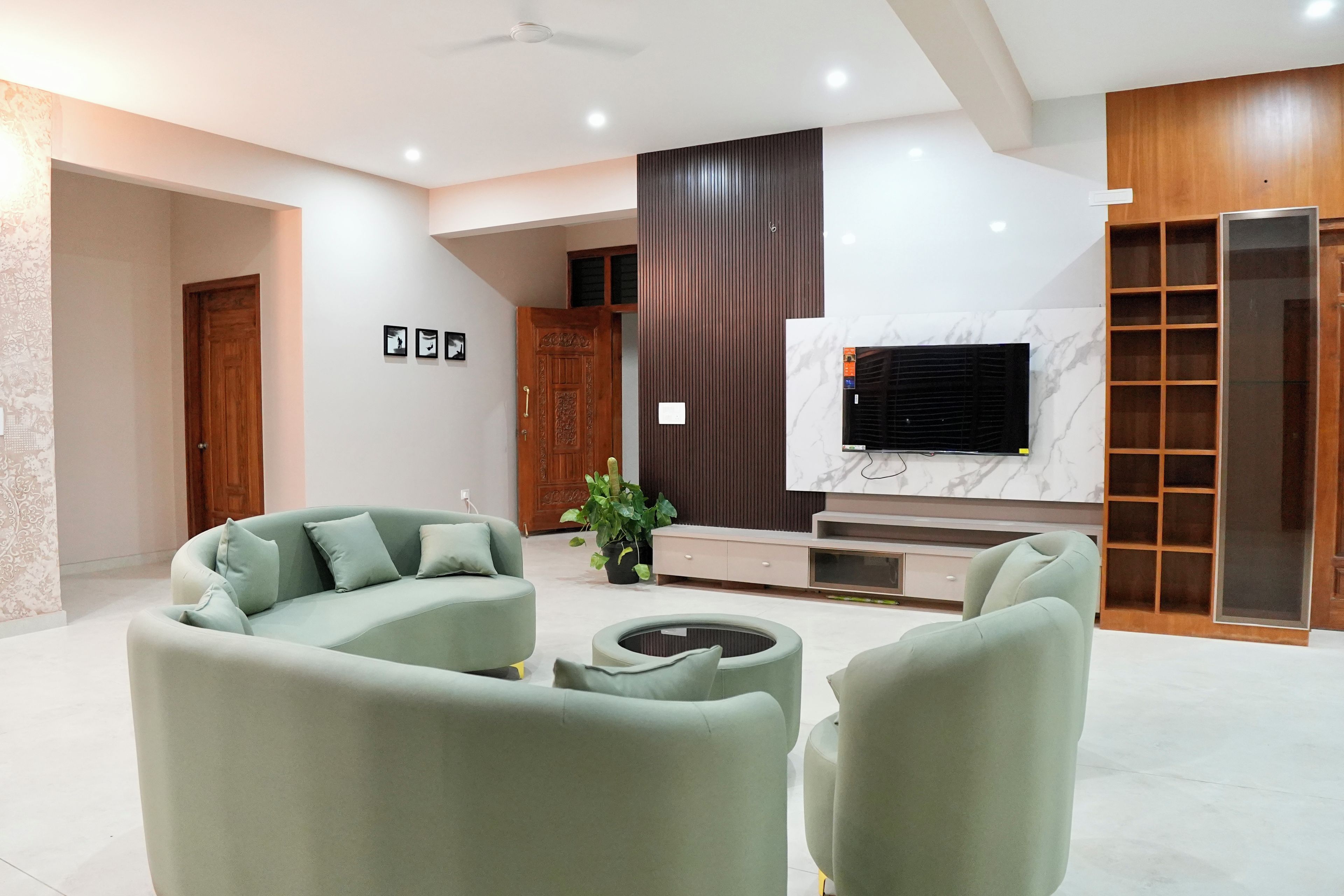 Una sala de estar moderna con un sofá modular, una mesa de centro y un televisor de pantalla plana montado en una pared de mármol.