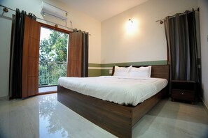 A bedroom with a large bed, a nightstand, a wall-mounted light, and an air conditioning unit.