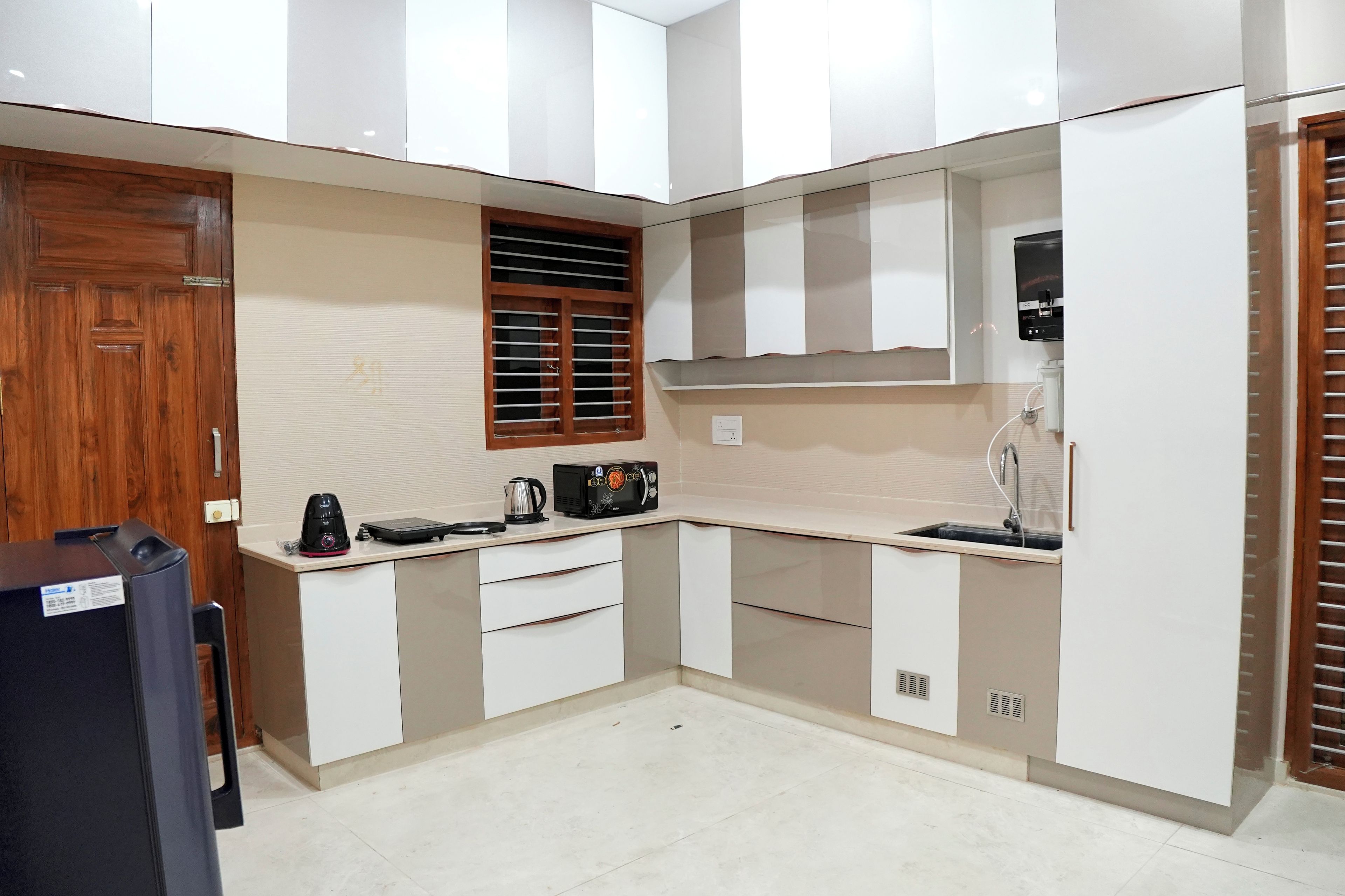 A compact kitchen with a built-in microwave, kettle, and coffee maker on the countertop.