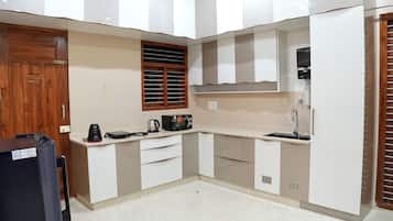 A compact kitchen with a built-in microwave, kettle, and coffee maker on the countertop.