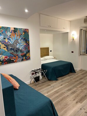 A room with two beds, a wooden floor, a wall-mounted radiator, and a colorful painting. - MANETTI ROOMS Double Room on Via Chiaia, 600 meters from the waterfront. (Napoli)