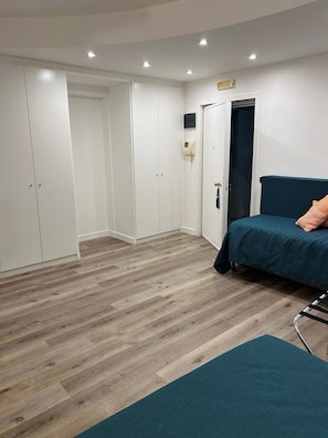 Ein Schlafzimmer mit einem Bett, einem Kleiderschrank, einer Tür und einem Lichtschalter an der Wand.